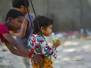 New Delhi: A child sips a soft drink while riding a swing during a hot summer af...